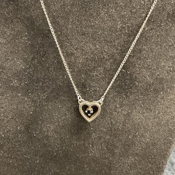 Delicate silver heart pendant necklace on a silver chain.