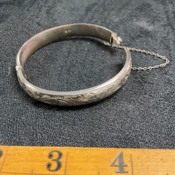 Intricate detailing on a vintage silver hinged bracelet.