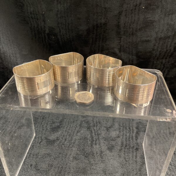 Group of four vintage silver napkin rings on display.