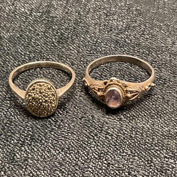 Close-up of two silver rings, one textured and one with amethyst.