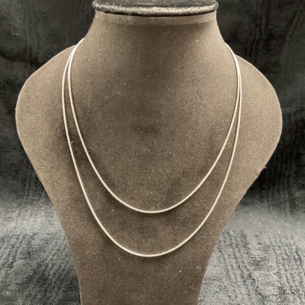 Two delicate silver snake chain necklaces on display.