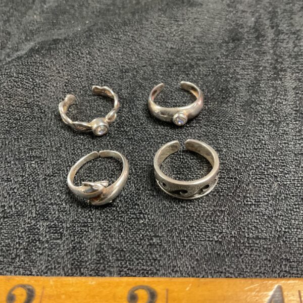 Close-up of four silver adjustable toe rings on a neutral background.