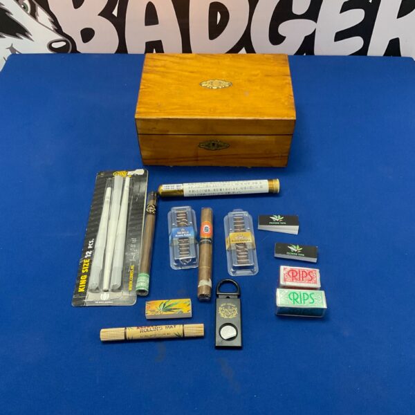 Wooden box containing smoking accessories, including cigars and rolling papers.