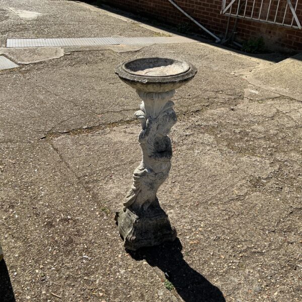 Weathered stone bird bath in a garden setting.