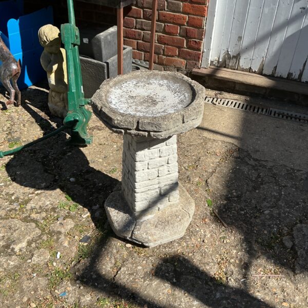 Tiered stone bird bath in a garden setting.