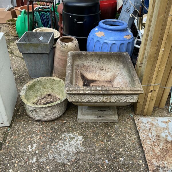 Pair of weathered stone garden planters in a garden setting.