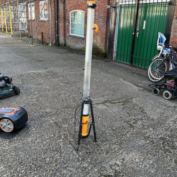 Tall portable site light on a paved surface.