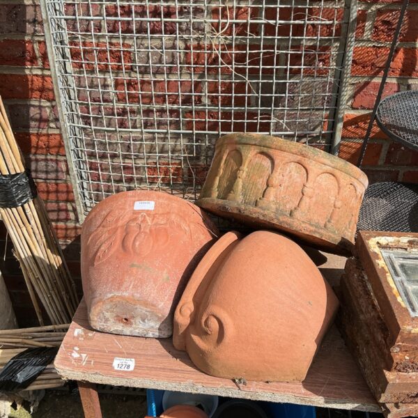 Vintage terracotta wall planters with face designs for garden decor.