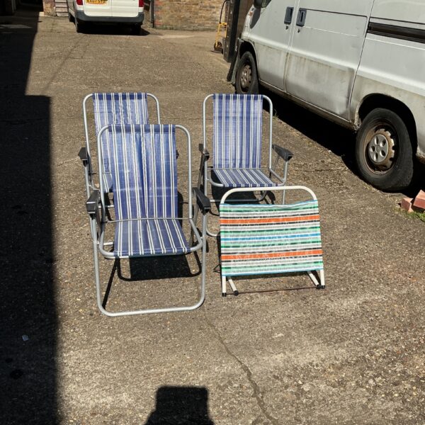 Three folding camping chairs in a garden setting.