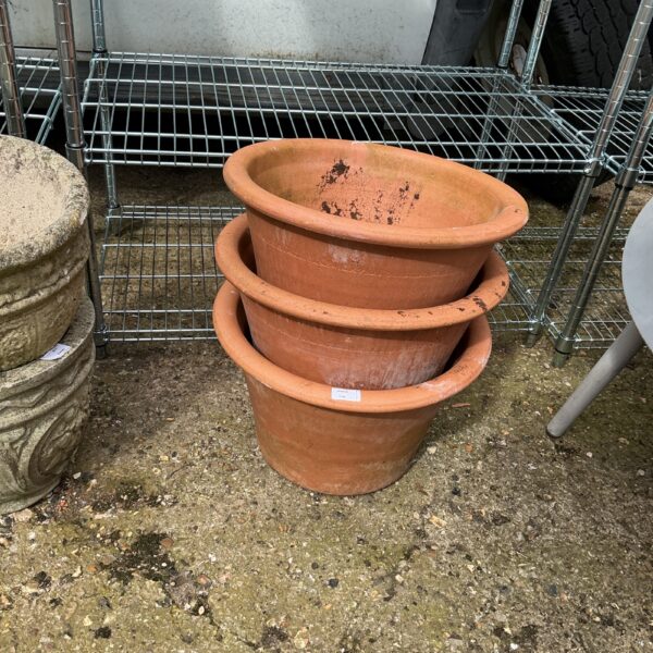 Set of three rustic terracotta garden pots for outdoor plants.