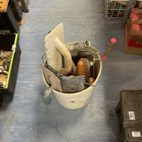 Metal bucket filled with various hand tools, including trowels and spatulas.