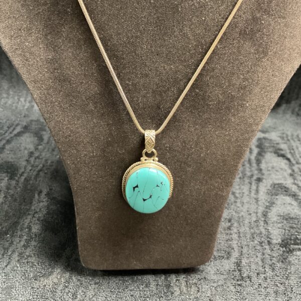 Silver pendant necklace with oval turquoise cabochon.