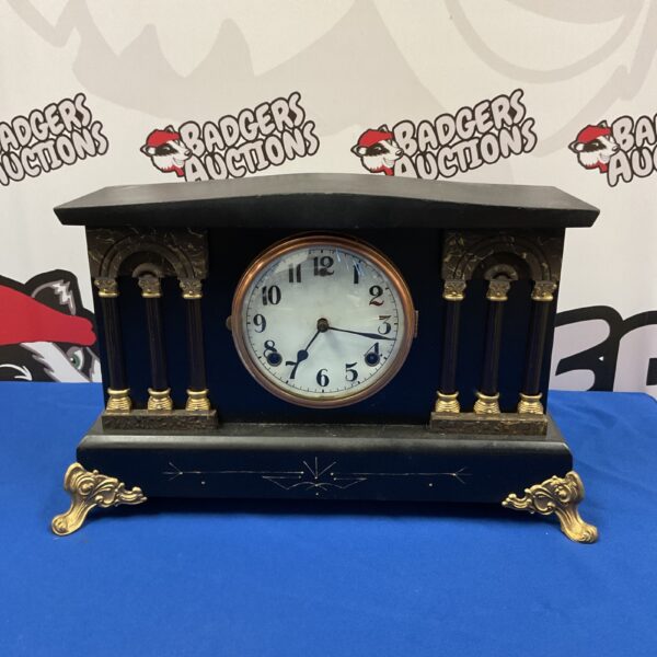 Ornate Victorian black mantle clock on display.