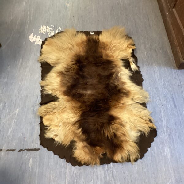 Vintage animal fur rug with scalloped edge, warm tones.