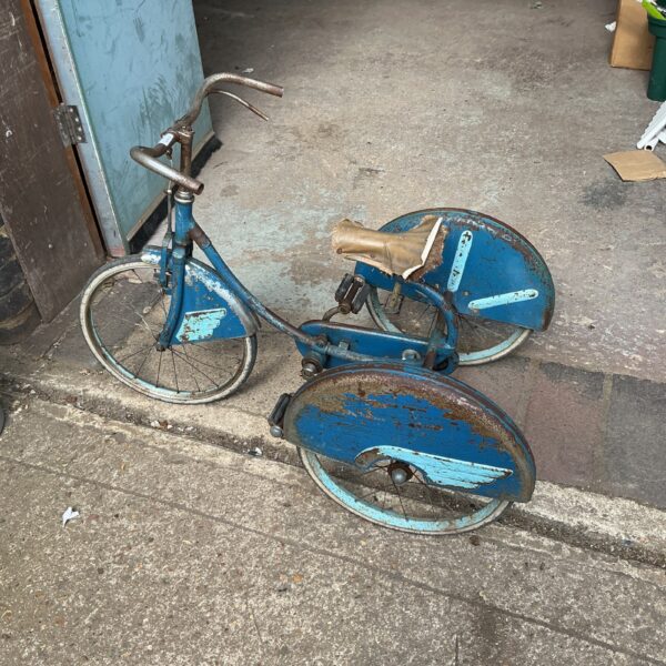 Blue vintage tricycle with metal frame and spoked wheels.