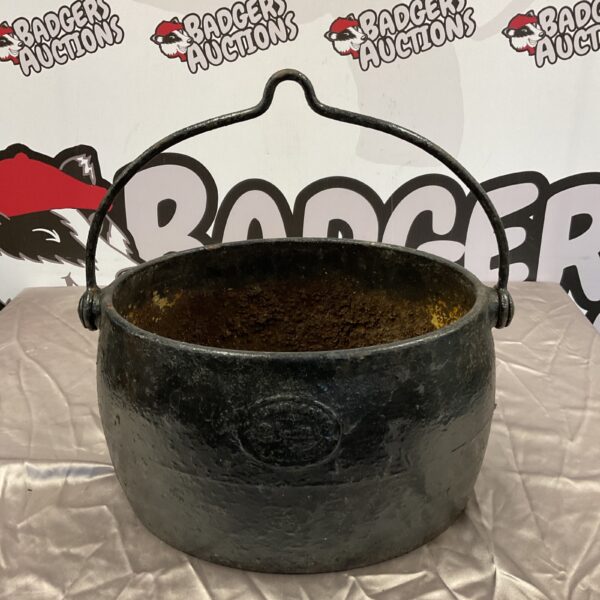 Vintage cast iron cauldron with handles and a hole in the base.