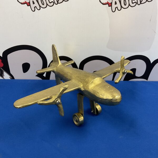 Golden vintage cast metal model aircraft on blue background.