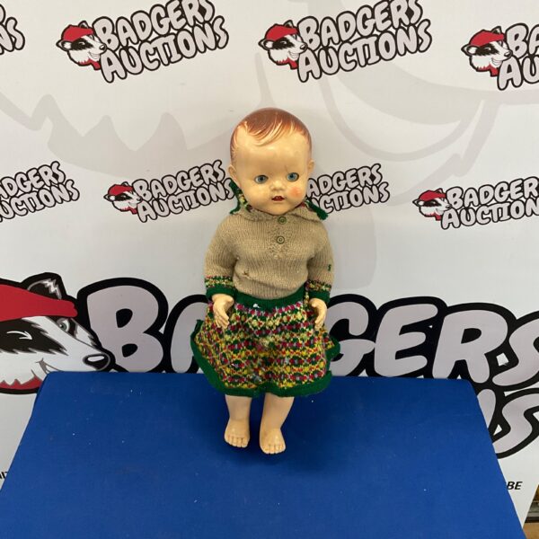 Vintage composition doll with patterned dress and painted features.