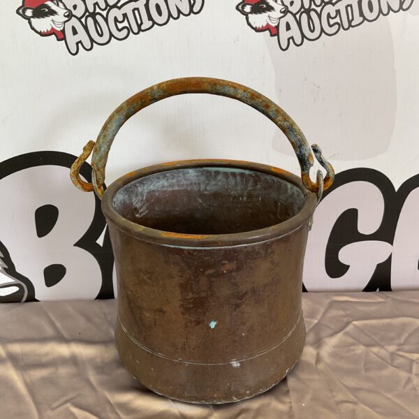 Vintage copper bucket with iron handle for rustic decor.
