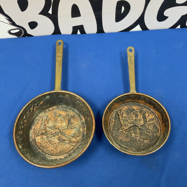 Vintage copper pan with embossed Swiss village scene.