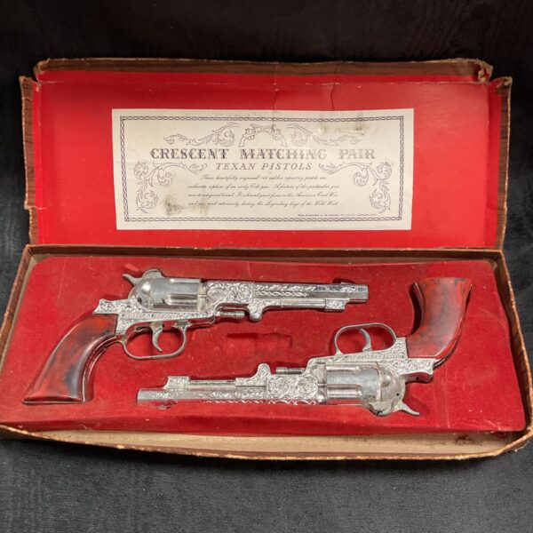 Vintage Crescent Texan cap gun pair, collectible toy pistols.