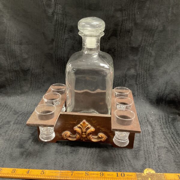Vintage decanter and shot glass set on wooden tray.