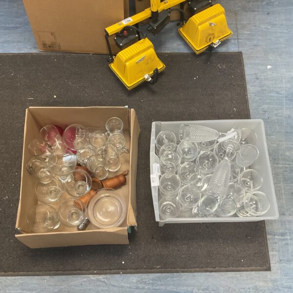 Assorted vintage and modern drinking glasses in a cardboard box.