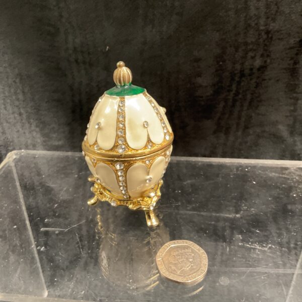 Cream enamel Fabergé style egg on gilded stand.
