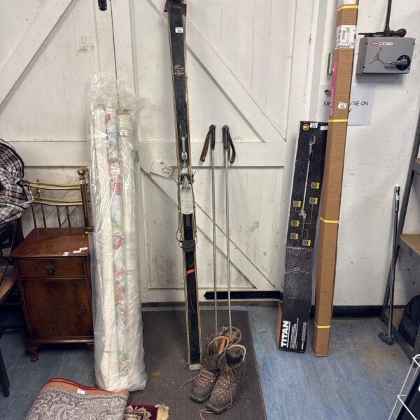 Vintage Fischer Pionier skis with poles and boots on a rug.