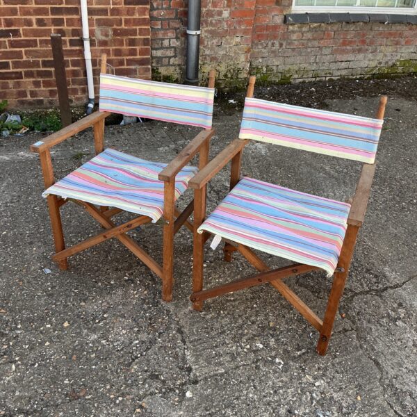 Two vintage folding directors chairs with striped canvas seats.