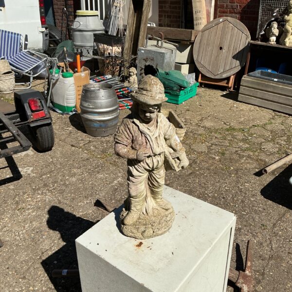 Weathered vintage garden boy ornament in a garden setting.
