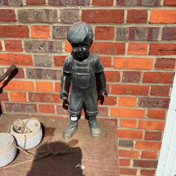 Weathered vintage garden boy ornament in a garden setting.