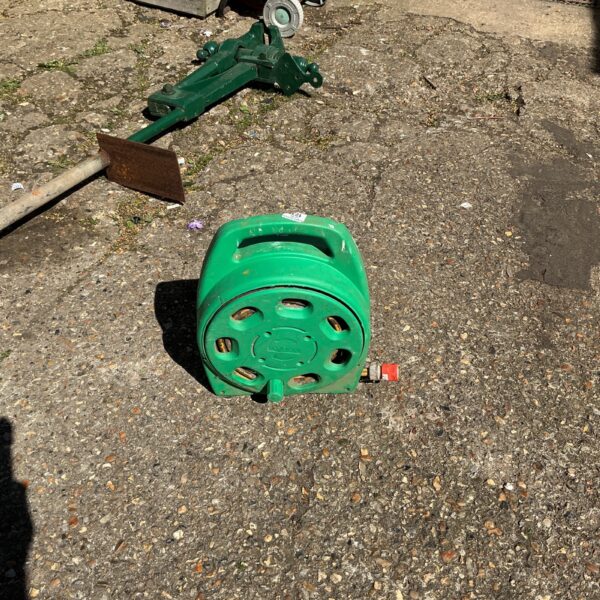 Vintage green garden hose reel with metal frame.
