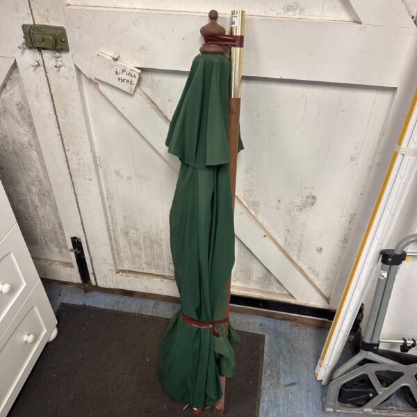 Vintage green garden parasol with wooden pole.