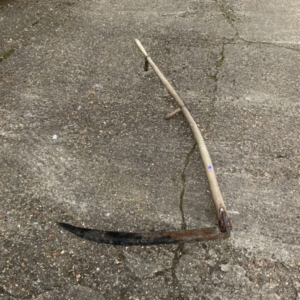 Vintage garden scythe with curved blade and wooden handle.