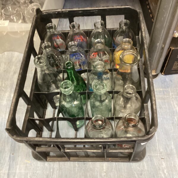 Assorted vintage glass bottles in a crate, collectible glassware.
