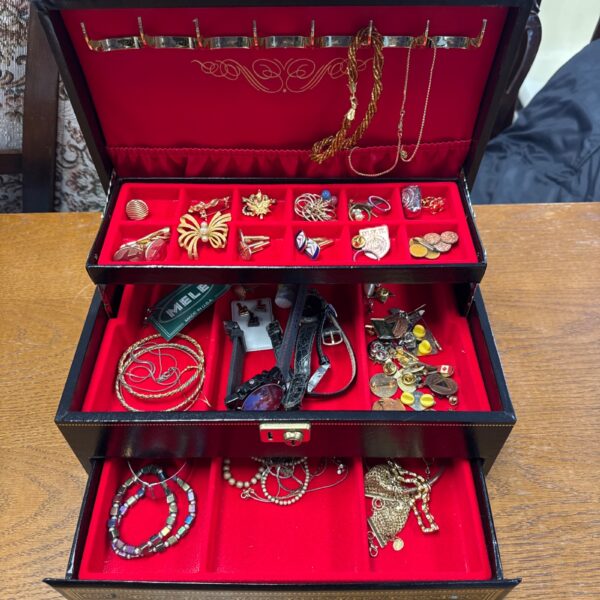 Open vintage jewellery box displaying costume jewellery and velvet lining.