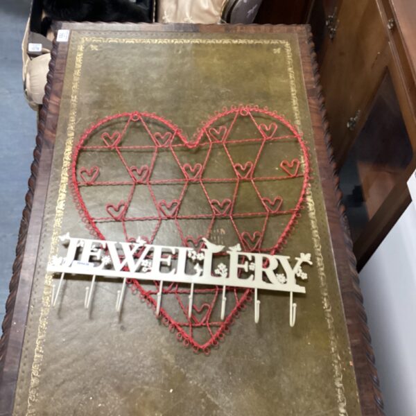 Vintage jewellery wall display with heart shape and red cord.