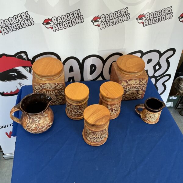 Vintage kitchen storage jars and glazed jugs on display.