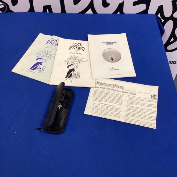 Vintage lock picking kit with manuals displayed open.