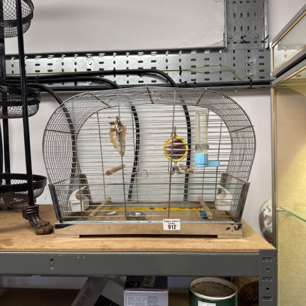 Vintage metal bird cage with a small perch inside.
