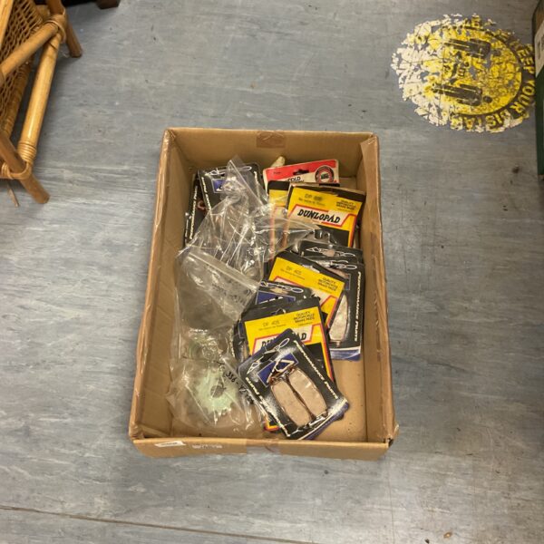 Vintage motorcycle brake pads and parts in a storage box.