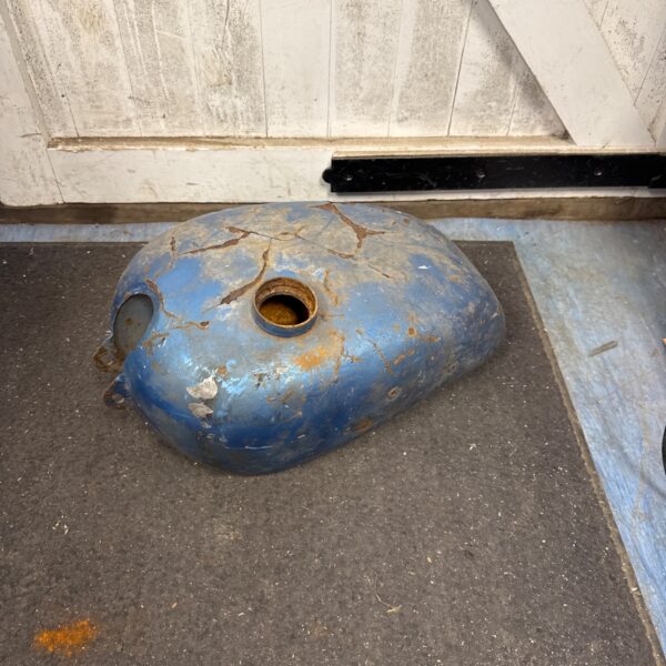 Faded blue vintage motorcycle fuel tank for restoration.