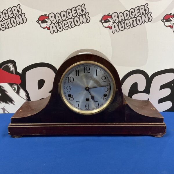 Vintage German Napoleon hat mantle clock on a blue background.