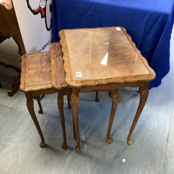 Vintage mahogany nest of tables with glass tops in a living room setting.