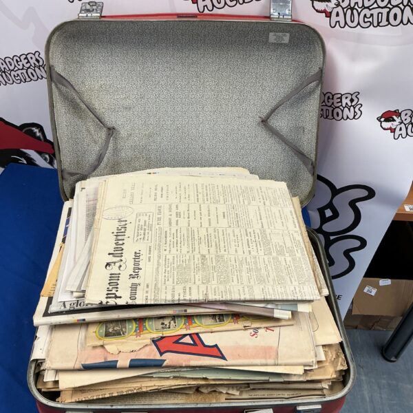 Open brown suitcase filled with vintage newspapers and magazines.