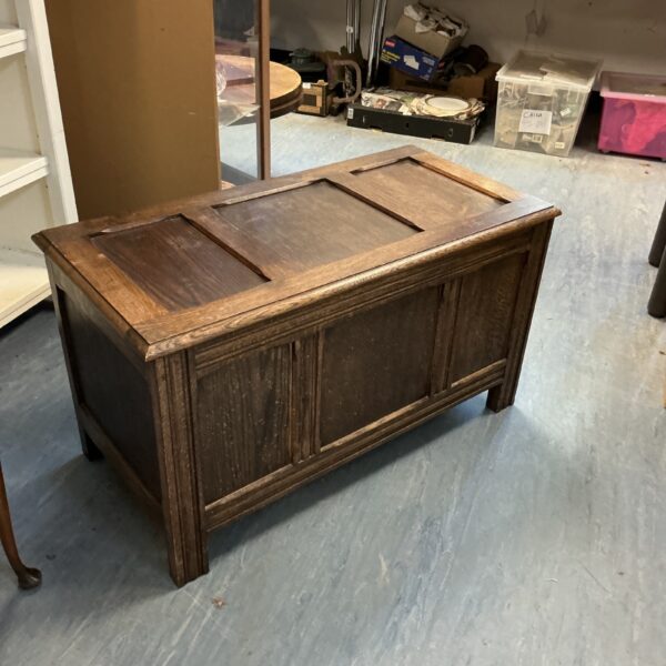 Front view of a vintage oak blanket chest with a lift-top lid.