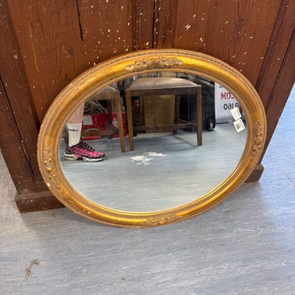 Vintage oval gilt mirror with ornate frame, ideal for home decor.