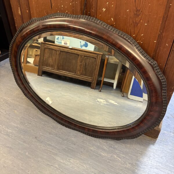Vintage oval mirror with bevelled glass and ornate frame.