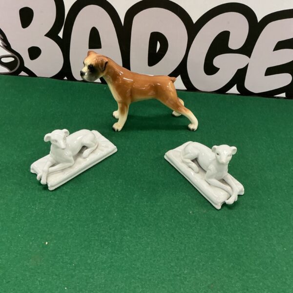 Vintage porcelain dog figurines displayed on a green surface.